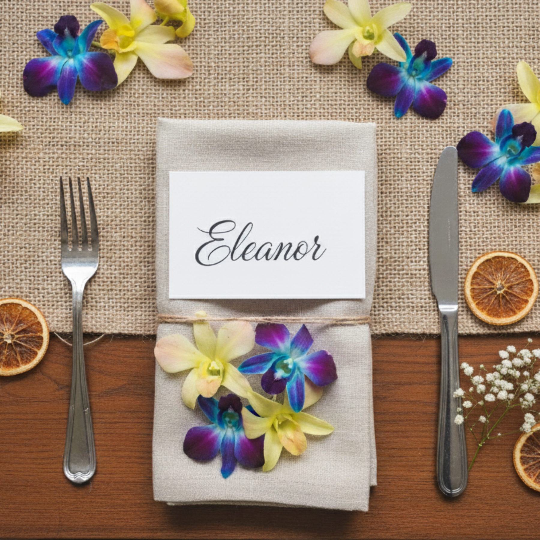 Wedding place setting with blue and yellow dendrobium orchids on burlap napkin and name card.”