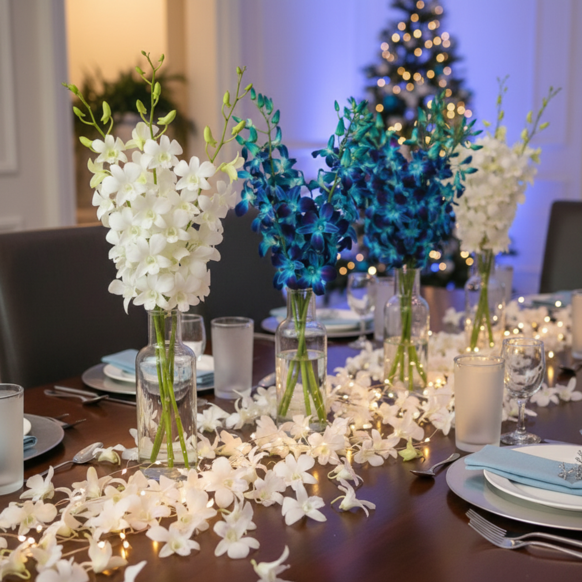 Holiday dinner table featuring blue and white dendrobium orchids with loose blooms scattered across the table runner