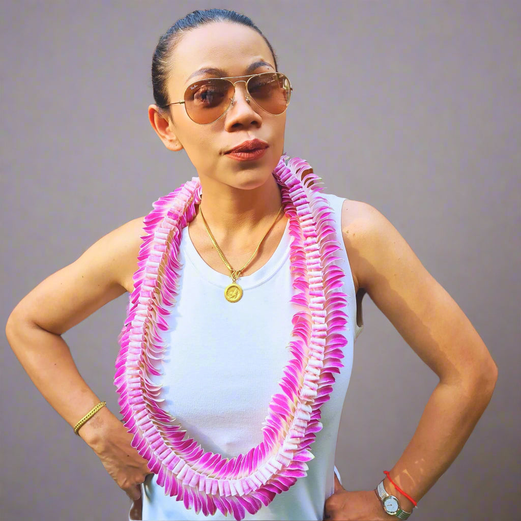 The Pink Dragon’s Tail Lei is a rare, double-braided orchid necklace featuring handwoven pink and white flowers. Its elegant, rope-like design makes it a standout accessory for tropical celebrations, including graduations, luaus, and destination weddings. Flown fresh from Thailand, this exquisite lei boasts superior craftsmanship and premium-quality orchids, ensuring it remains fresh and vibrant throughout your special event.